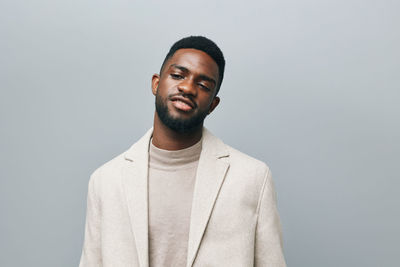 Portrait of young man standing against gray background