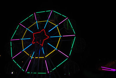 Illuminated ferris wheel against sky at night