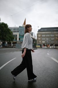 Full length of woman standing on road against buildings