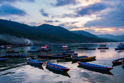 Boats moored in lake against mountain range
