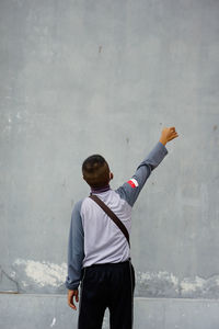 The indonesian nationality man faces back poses and raises his right hand.