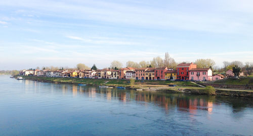 Buildings by river against sky