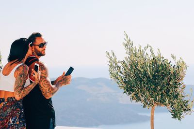 Young man using smart phone against sky