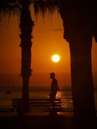 Silhouette people at beach against sky during sunset