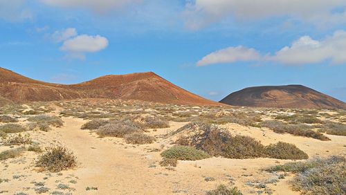 Scenic view of desert against cloudy sky