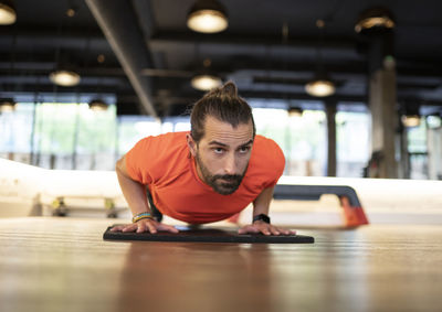 Bearded adult sportsman doing push-ups during fitness training in contemporary gym