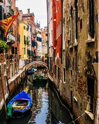 Boats moored in canal amidst buildings in city