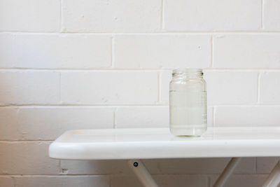 Close-up of white bottle on wall at home