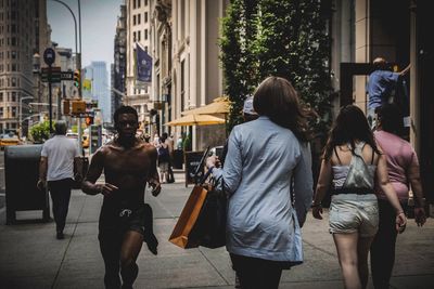 Rear view of people walking on street in city