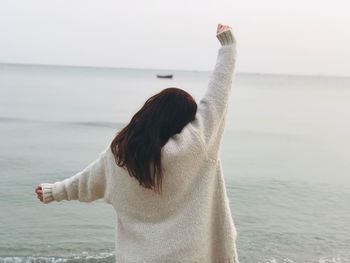 Rear view of woman standing at beach during sunset