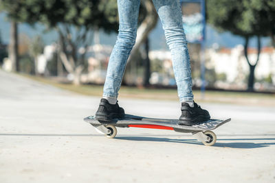 Low section of man skateboarding on road