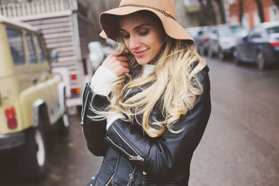 Close-up of young woman wearing hat at city