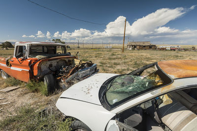 Abandoned car on field against sky