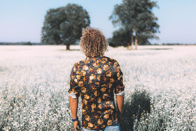 Rear view of man standing amidst flowering plants