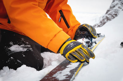 Close-up of a man's hand, adjusting the skis against the background of snow and things, putting on
