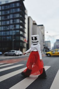 Woman wearing box while walking on road against sky