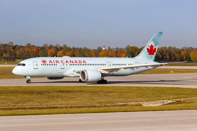 Side view of airplane on airport runway against sky