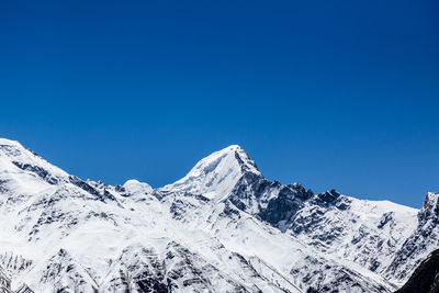 Scenic view of snowcapped mountains against clear blue sky