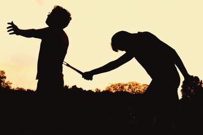 Silhouette people standing against clear sky during sunset