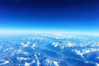 Aerial view of snowcapped landscape against blue sky