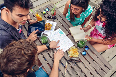 High angle view of friends looking at map while sitting in restaurant