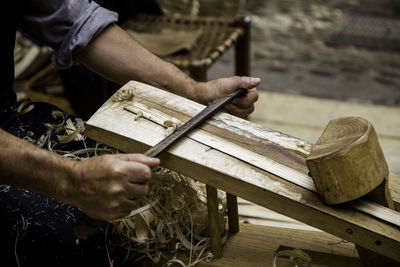 Midsection of carpenter shaving wood in workshop