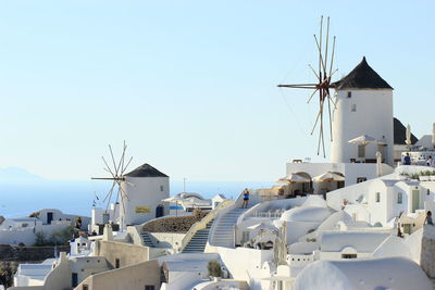 Traditional windmills in village at santorini against clear sky