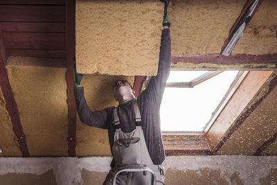 Roof insulation, worker filling pitched roof with wood fibre insulation