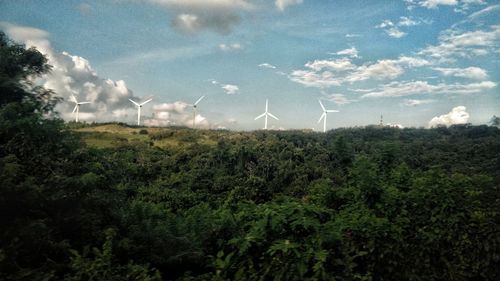 Wind turbines on field against sky