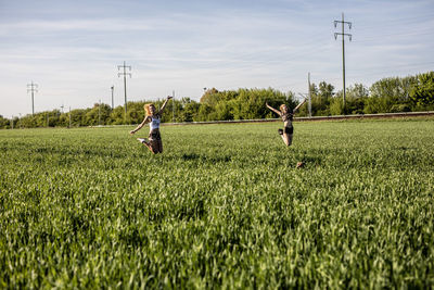 Friends enjoying on grassy field against sky