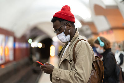 Man wearing mask using smart phone at subway station