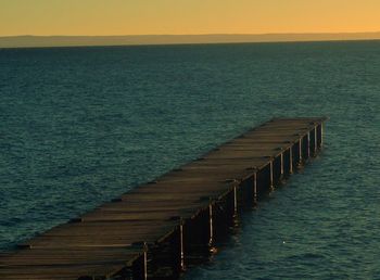 Pier over sea against sky during sunset