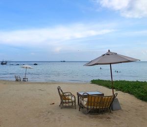 Deck chairs on beach against sky