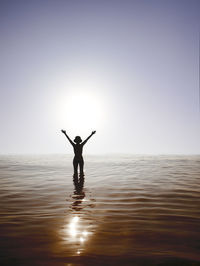 Silhouette woman standing at sea against clear sky