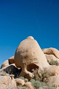 Low angle view of sand against clear blue sky