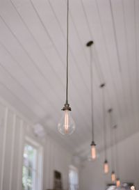 Low angle view of illuminated light bulbs hanging from ceiling