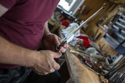 Midsection of woman repairing violin string