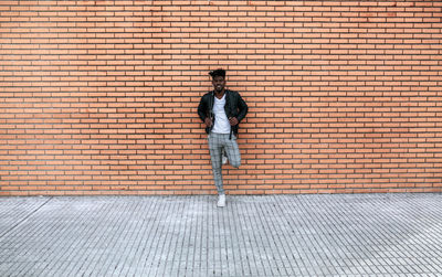 Full length of man standing against brick wall