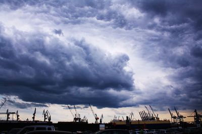 Low angle view of silhouette cranes against sky during sunset