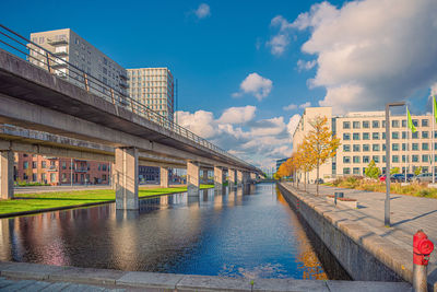 Buildings by river against sky