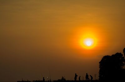 Silhouette trees against orange sky during sunset