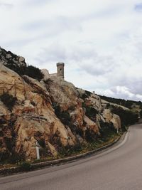 Road by rocky mountains against sky