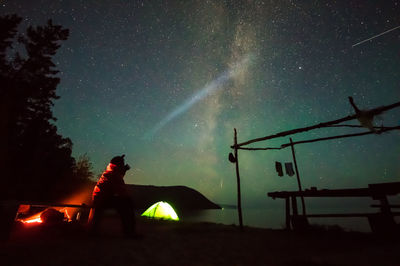 Low angle view of silhouette skywatcher against sky at night