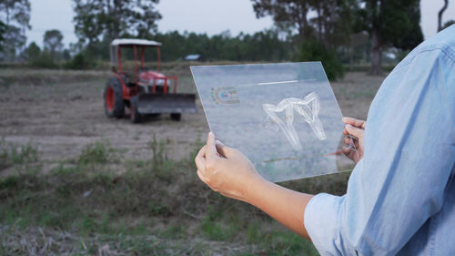 Midsection of woman holding umbrella on field