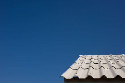 Low angle view of building roof against clear blue sky