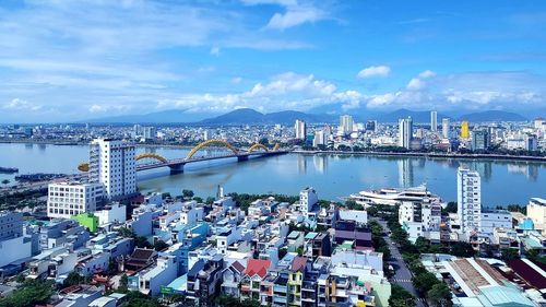 High angle view of city by river against sky