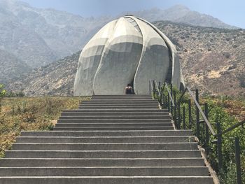 Rear view of woman walking on stairs leading towards mountain