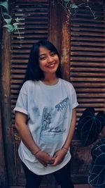 Portrait of young woman standing against wall