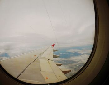 View of airplane wing over clouds seen through window