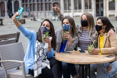 Smiling sisters taking selfie at cafe